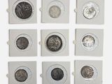 six types différents de pièces d'argent dans une boîte posée sur une surface blanche