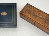 an old wooden box with a black cover and a wooden box with a gold leaf on it