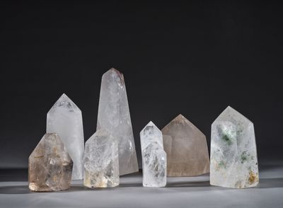 un ensemble de cinq cristaux de quartz de tailles différentes posés sur une surface blanche