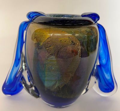 a glass vase with a blue handle sitting on a table