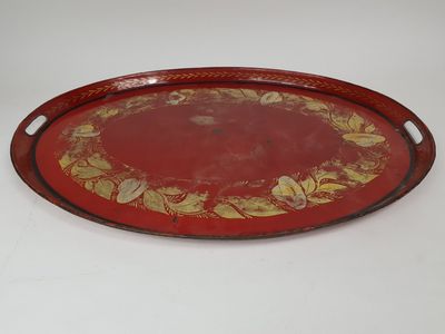 un plateau rouge et doré orné d'un motif floral