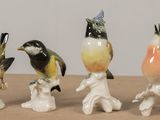 quatre figurines d'oiseaux posées sur une table en bois