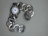 un bracelet en argent orné d'une montre, posé sur une table