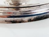 a silver plate on a white table with a silver spoon