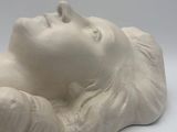 a white sculpture of a woman laying down on a white surface