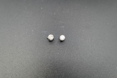 a pair of diamond stud earrings on a black surface