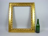 a green bottle next to a picture frame on a white surface
