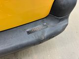 a close up of a yellow car with a small hole in the bumper