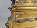 a gold clock with a statue on top of it