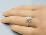 la main d'une femme à laquelle est passée une bague de fiançailles sertie d'un diamant