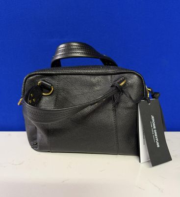 un sac à main noir muni d'une étiquette, posé sur une table