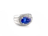a close up of a ring with a blue stone surrounded by diamonds