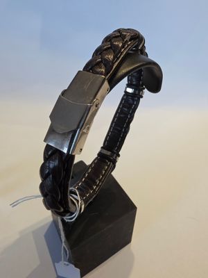 bracelet en cuir noir muni d'un fermoir argenté sur un support noir