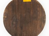 a close up of a round wooden table with a yellow label on it