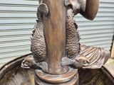 a bronze statue of a woman drinking water from a fountain