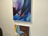 des tableaux accrochés au mur dans une pièce où se trouvent une table et des chaises