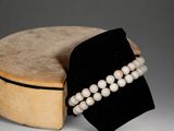 a white pearl bracelet and a wooden box on a table
