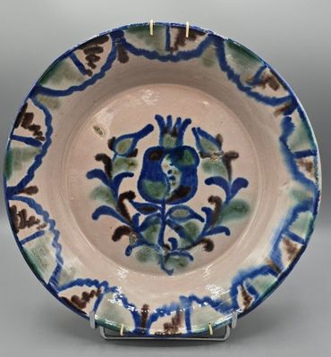 Plat creux en faïence à décor de fleurs et feuillages.