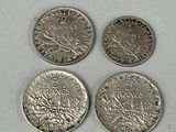 four different types of silver coins on a white surface