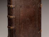 an old book with a brown leather cover sitting on top of a table