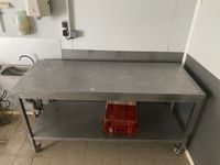 Une table rectangulaire en acier à tablette médiane, sur rou…