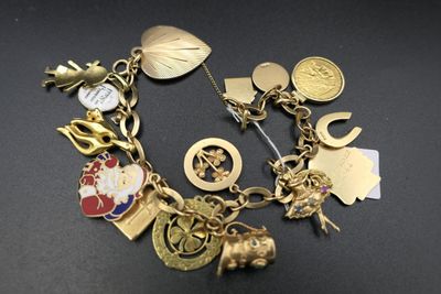 un bracelet en or orné de nombreuses breloques, posé sur une table