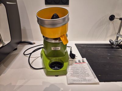 un extracteur de jus vert et jaune posé sur un plan de travail