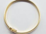 gros plan d'un bracelet en or sur une surface blanche