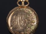 an antique gold pocket watch with engraved initials on the dial