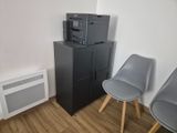 two chairs in the corner of a room with a microwave on top of a cabinet