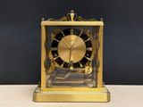 a gold clock sitting on a table with a black background
