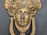 an image of a brass door knock with a woman ' s face on it