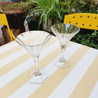 two martini glasses sitting on a table with a yellow chair