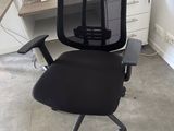 a black office chair sitting in front of a computer desk