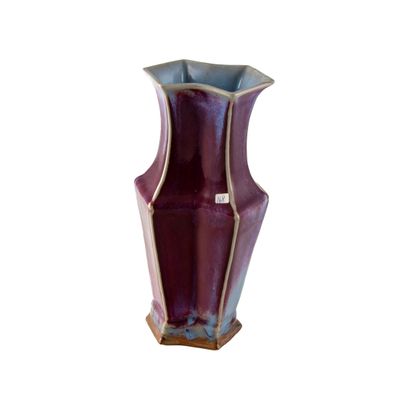 un vase violet posé sur une surface blanche