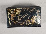a close up of a small black and gold box on a white surface