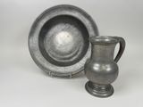 a silver cup and saucer sitting next to each other