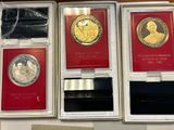 three gold and silver coins are in a box on a table