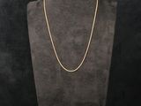 a gold necklace on a mannequin with a black background