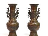 two bronze vases sitting side by side on a white surface