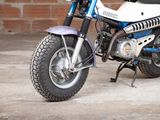 a small blue and white motorcycle parked in front of a brick wall