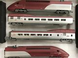 trois trains rouges et argentés posés sur une surface blanche