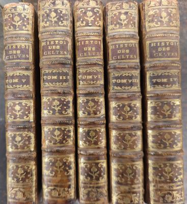 six vieux livres sont empilés sur une table