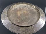 two silver plates with designs on them sitting on a table