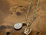 a close up of a necklace on a wooden surface with a clock
