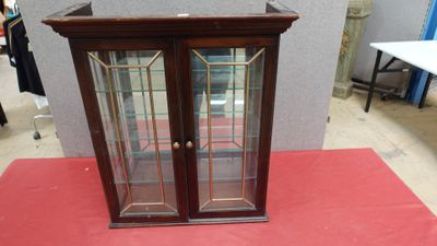 une vitrine aux portes vitrées posée sur un tapis rouge