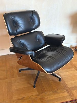 une photo d'un fauteuil et d'un repose-pieds en cuir noir dans un salon