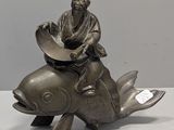 une statue représentant un homme assis sur un poisson