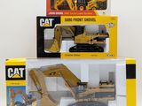 three toy construction vehicles in boxes on a white surface