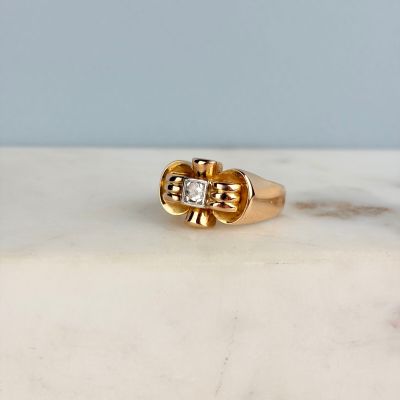 une photo d'une bague en or et diamants posée sur une surface en marbre
